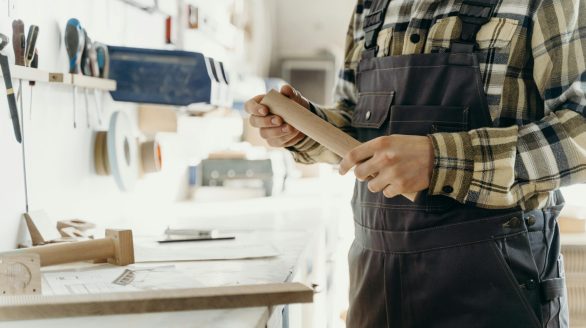 A focused craftsman shaping wood by hand in a well-lit indoor workshop, emphasizing skill and precision.